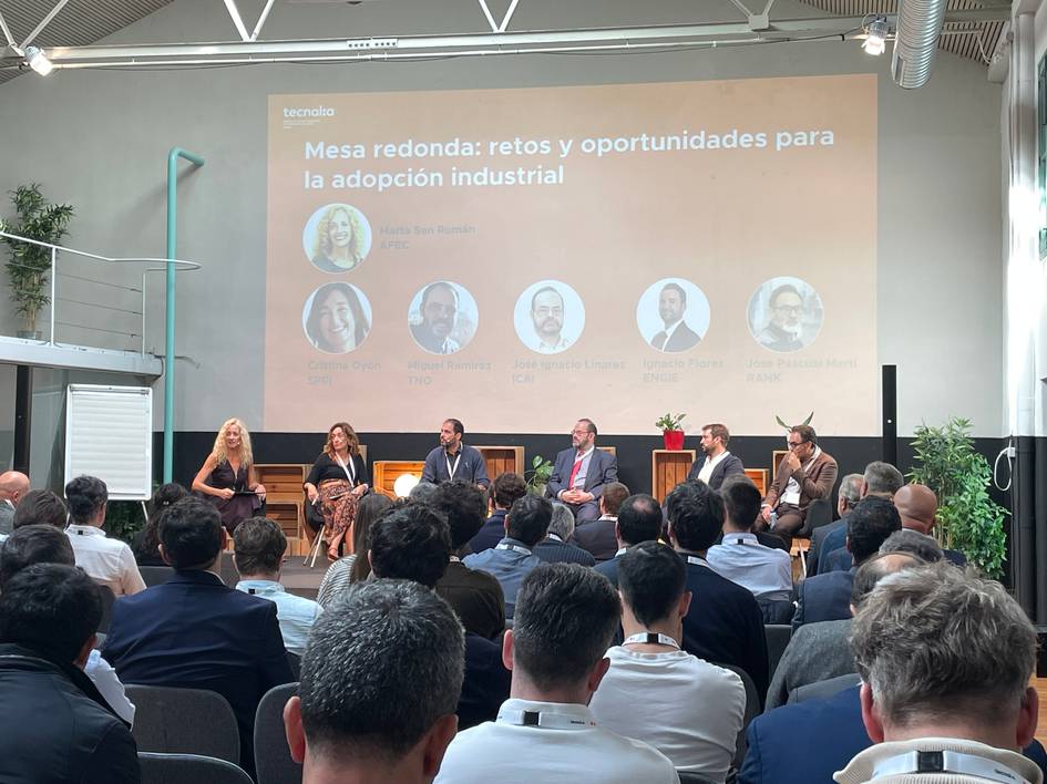 Una mesa redonda sobre los retos y oportunidades para la adopción industrial con varios oradores en un evento.