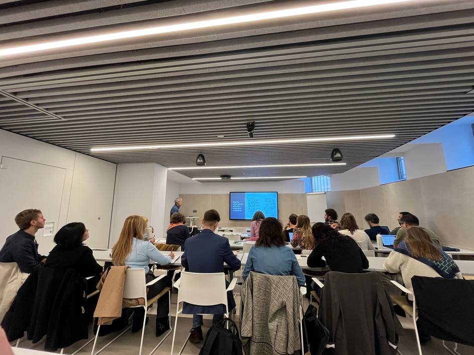 Una sala de reuniones donde un grupo de personas asiste a una presentación.