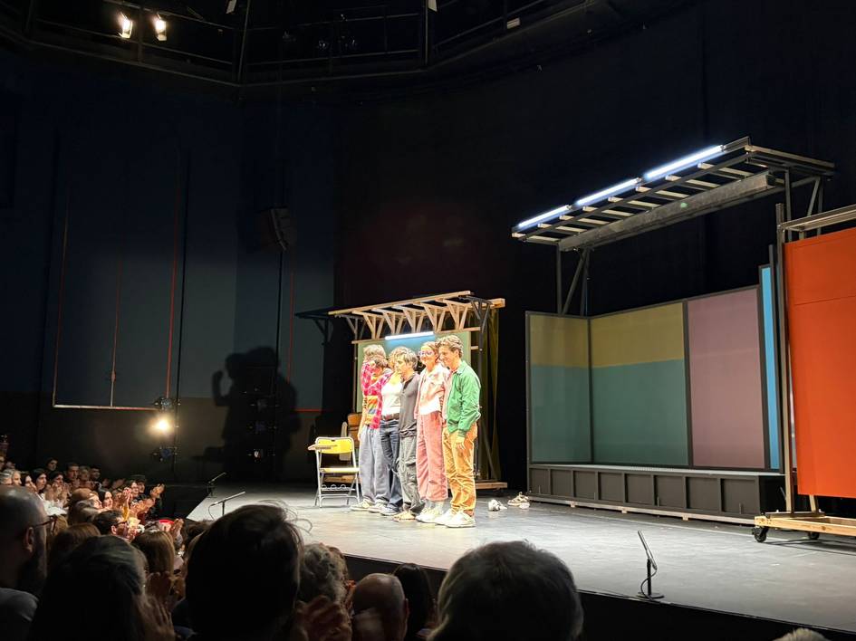 Un grupo de actores en un escenario reciben aplausos del público al final de una representación teatral.