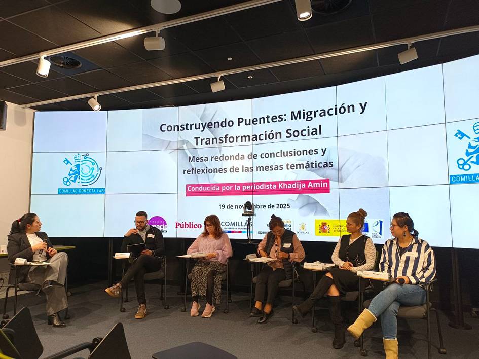 Una mesa redonda sobre migración y transformación social, con varios panelistas y una presentadora en un entorno moderno.