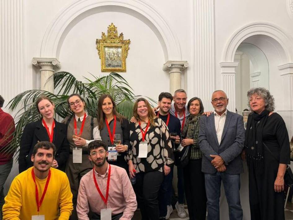 Un grupo de personas posando en un evento, con decoraciones elegantes y plantas de fondo.