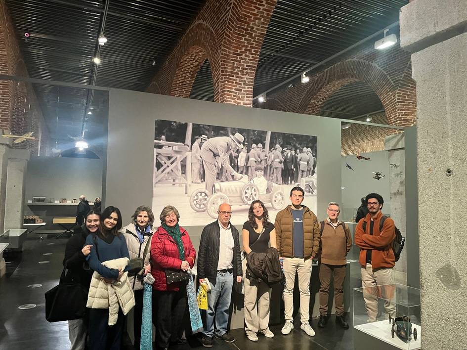 Un grupo de personas sonríe para la foto en un museo con una exposición fotográfica de fondo.