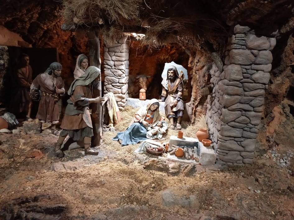 Representación de un nacimiento con figuras que imitan a José, María y el niño Jesús en un entorno rústico y detallado.