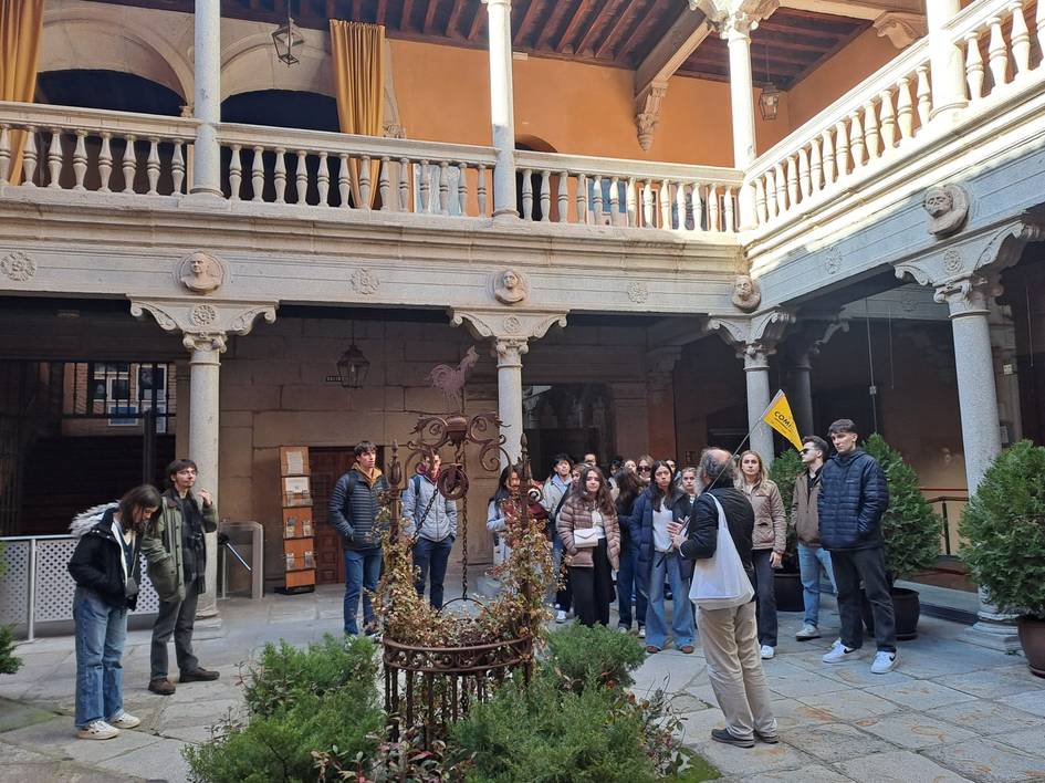 Un grupo de personas en una visita guiada en el patio de un edificio antiguo con arquitectura clásica.