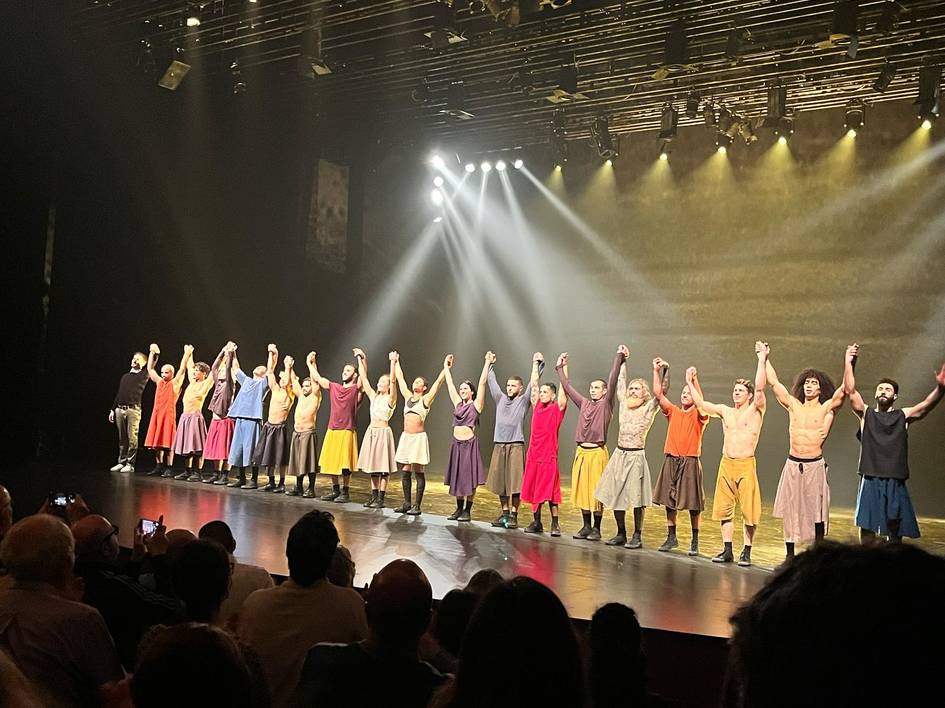 Un grupo de artistas hace una reverencia en el escenario de un teatro tras una presentación.