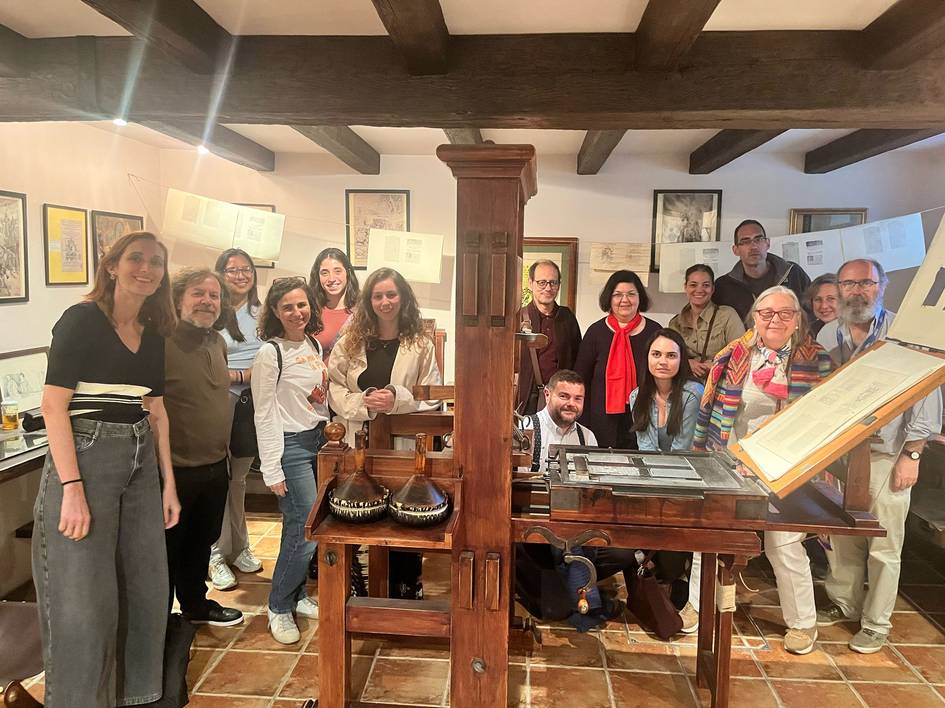 Grupo de personas posando en un entorno que parece un taller de impresión antigua.
