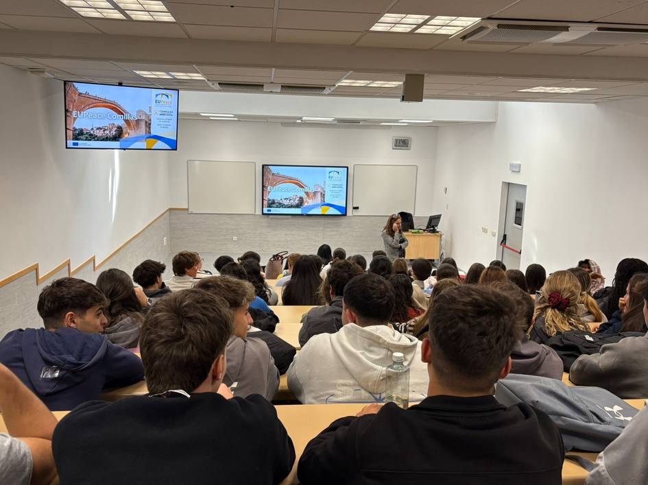 Una sala de clases con estudiantes prestando atención a una presentación.