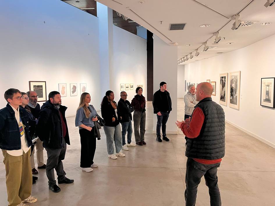 Un grupo de personas escucha atentamente a un guía en una galería de arte.