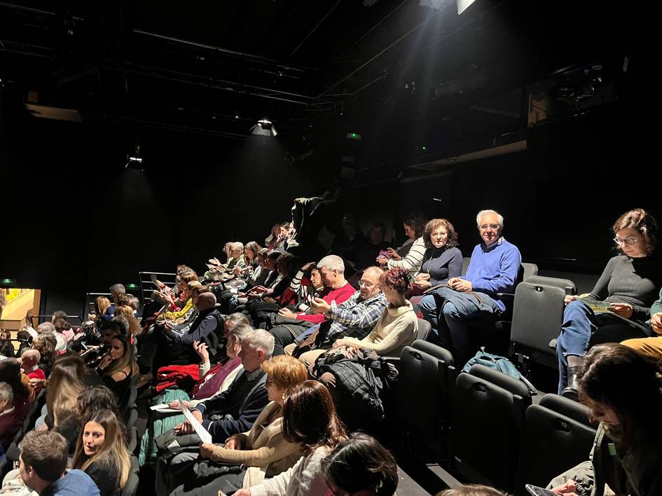 Un grupo de personas sentadas en un teatro, con la atención dirigida hacia el escenario.