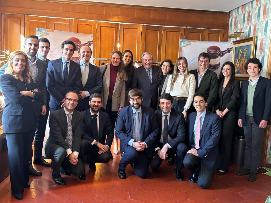 Un grupo de profesionales posa juntos en una sala con un fondo de paneles de madera y decoraciones coloridas.