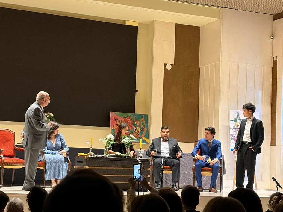 Una representación teatral con varios actores en el escenario, rodeados de un público atento.
