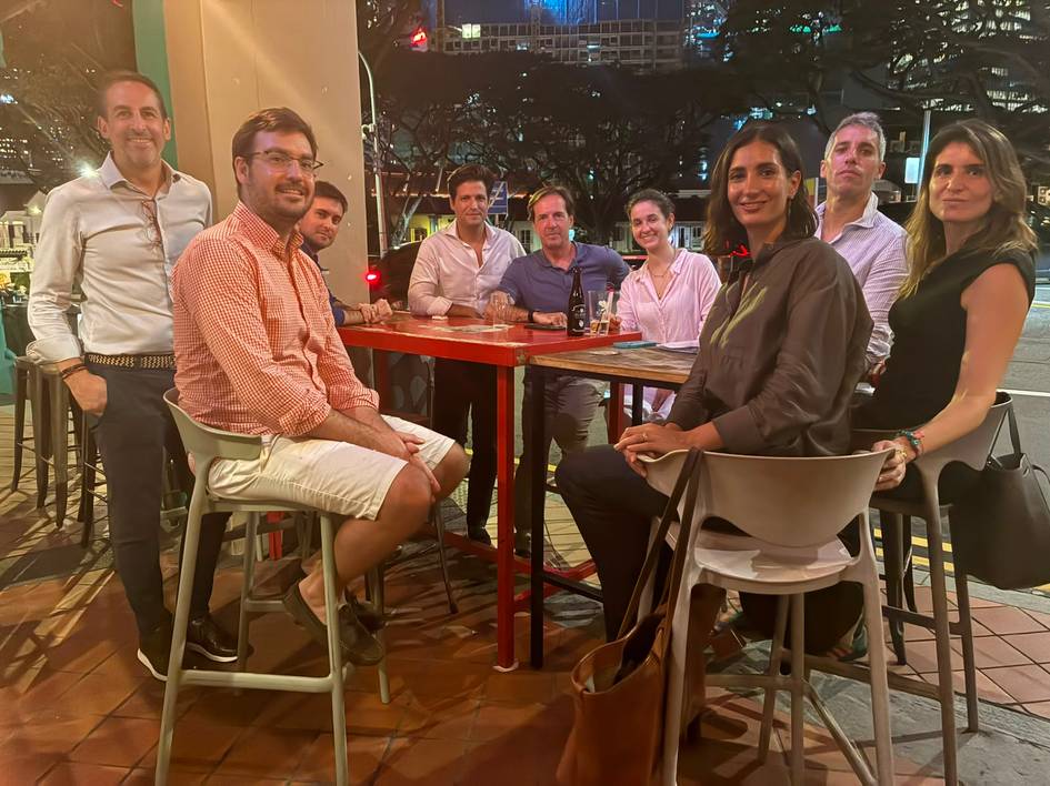 Un grupo de personas se encuentra reunido en una mesa en un bar durante la noche.