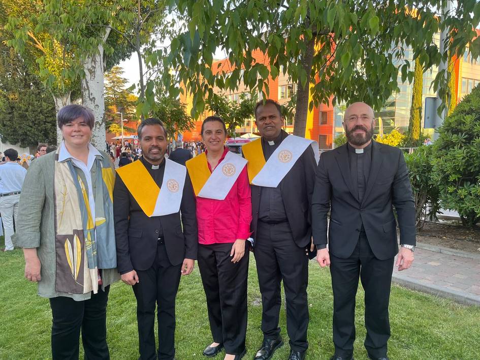 Un grupo de cinco personas vestidas formalmente posan para la foto al aire libre.