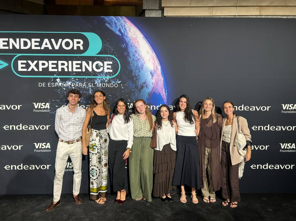 Grupo de personas posando en un evento de Endeavor en frente de una pantalla que muestra el logo de la organización.