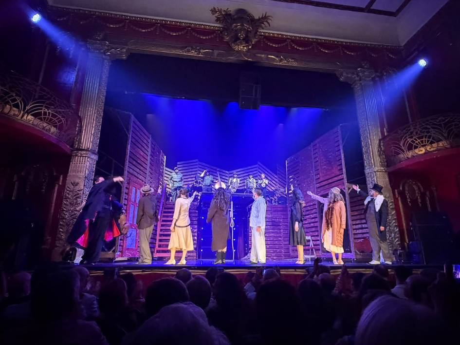 Un grupo de actores se presenta en escena durante una actuación teatral en un teatro.
