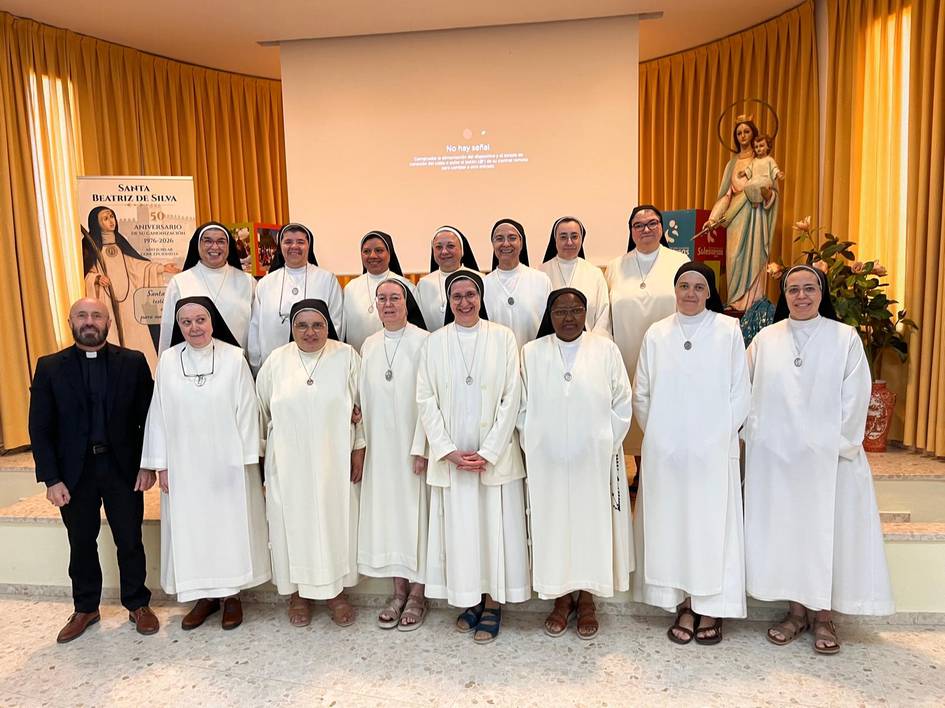 Un grupo de religiosas y un sacerdote posan juntas en un ambiente interior con decoraciones religiosas.