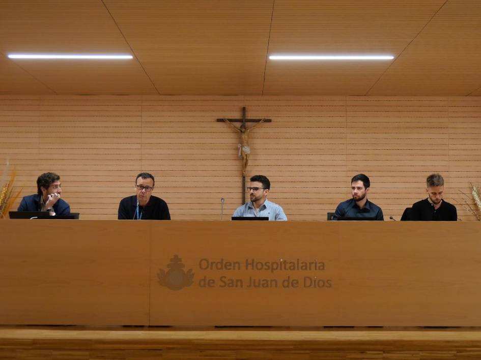 Un grupo de cinco hombres se sienta frente a un podio en un ambiente formal.