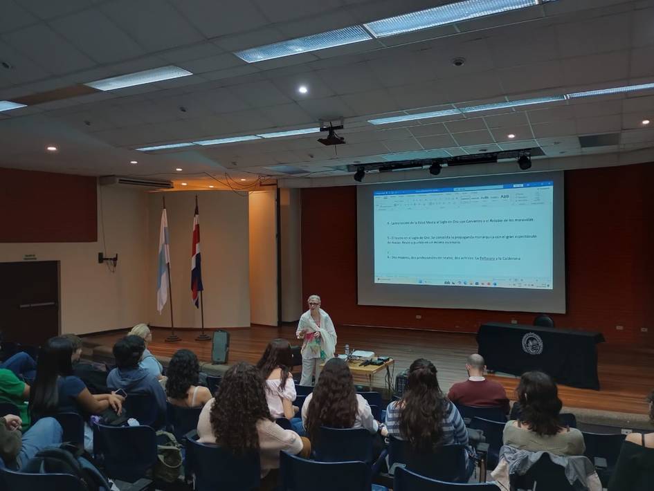 Una presentación en un aula con un ponente frente a un grupo de personas sentadas.