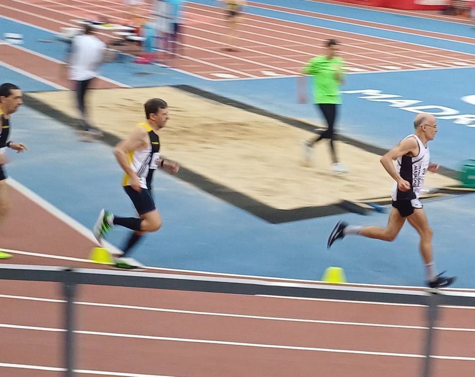 Un grupo de corredores compite en una pista de atletismo cubierta.