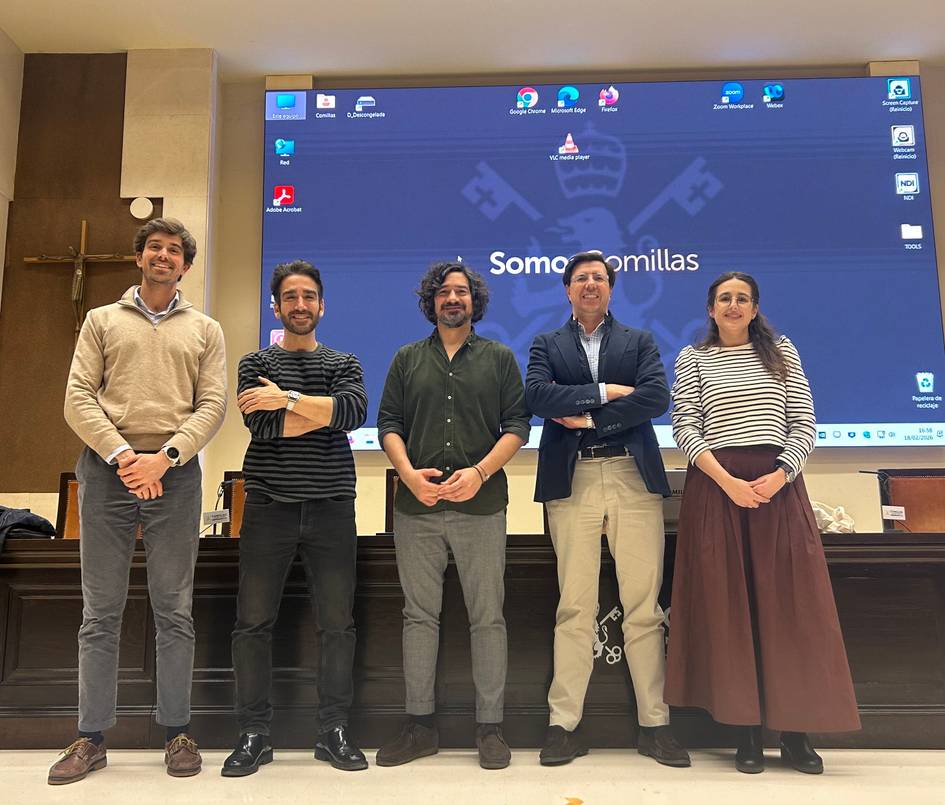 Un grupo de cinco personas posando frente a una pantalla en un evento.