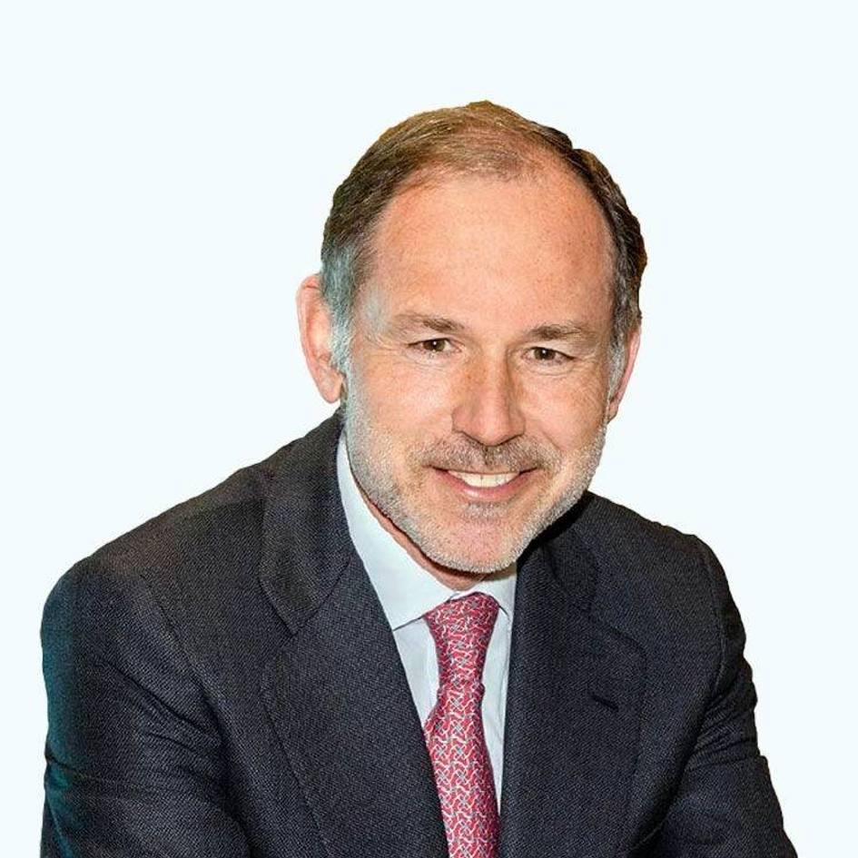 A professional portrait of a smiling man wearing a suit and a red tie.