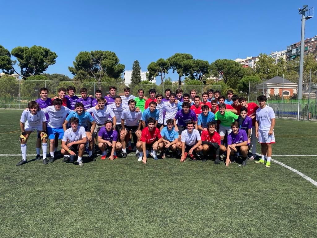Grupo de jóvenes en un campo de fútbol posando juntos bajo el sol.