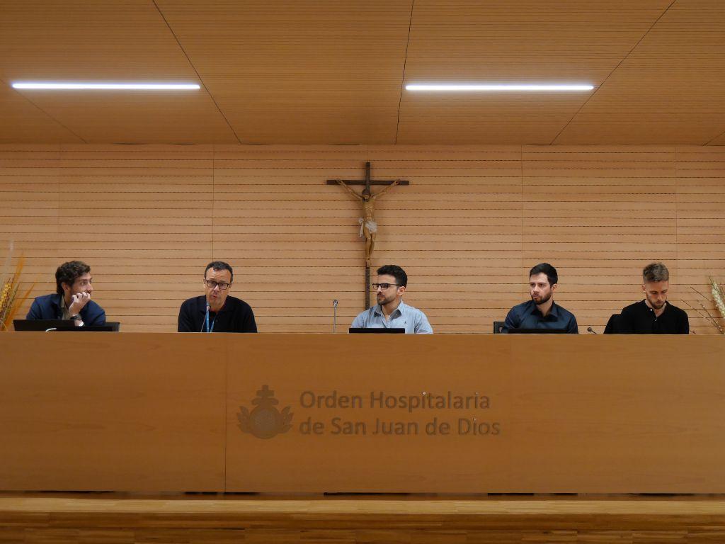Un grupo de cinco hombres se sienta frente a un podio en un ambiente formal.