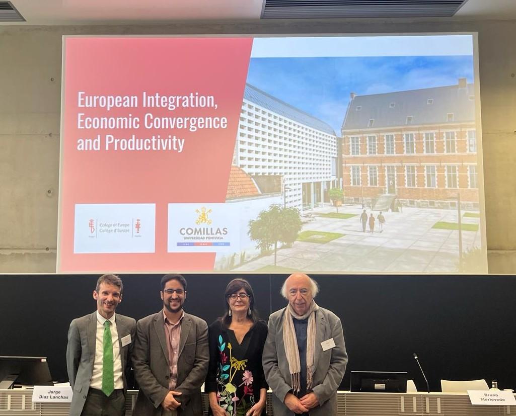 Four people standing in front of a presentation screen displaying a title about European Integration, Economic Convergence and Productivity at an academic conference.