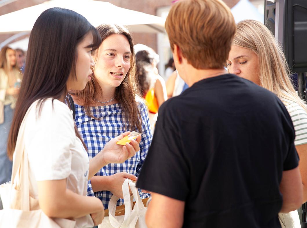 A group of young adults engaged in conversation at an outdoor event.