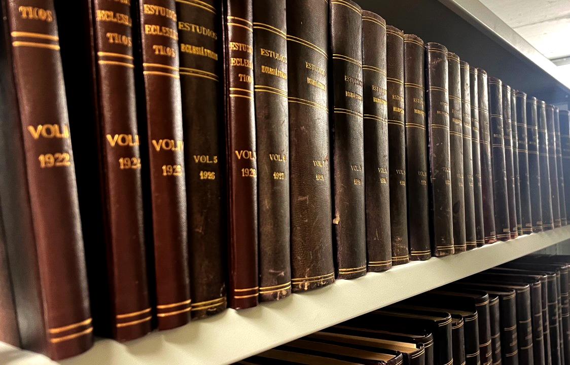 Una estantería con numerosos volúmenes de la revista Estudios Eclesiásticos encuadernados en cuero.