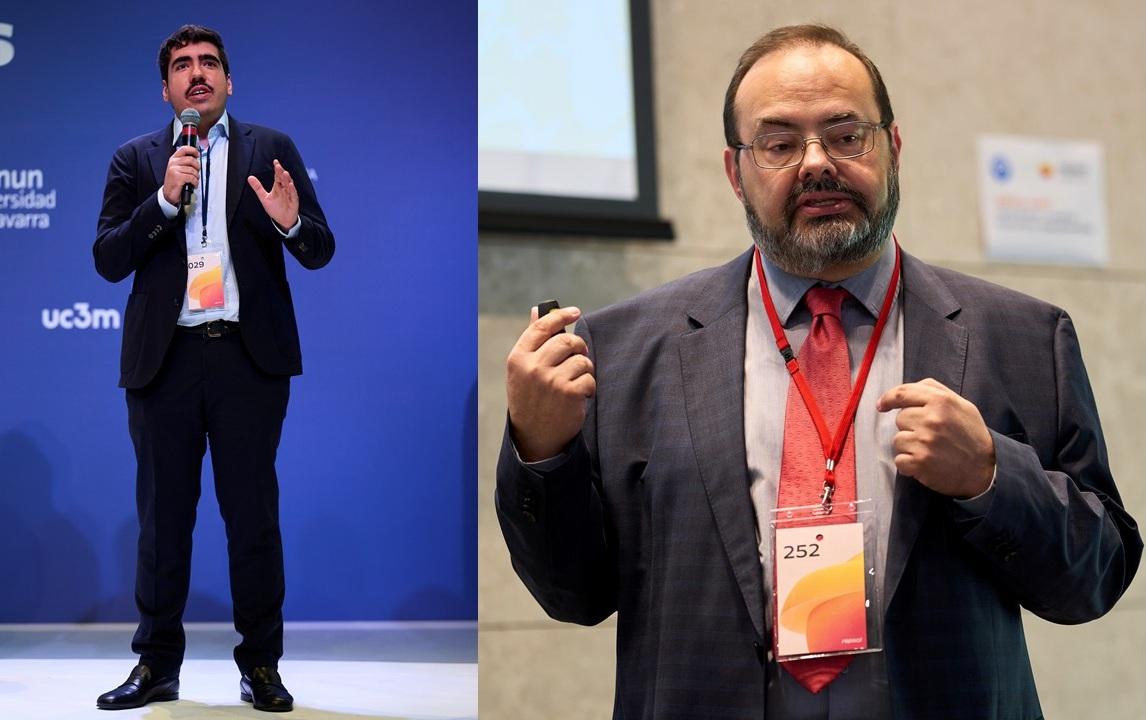 Dos hombres dan charlas en un evento, uno de pie hablando y el otro gesticulando frente a una pantalla.