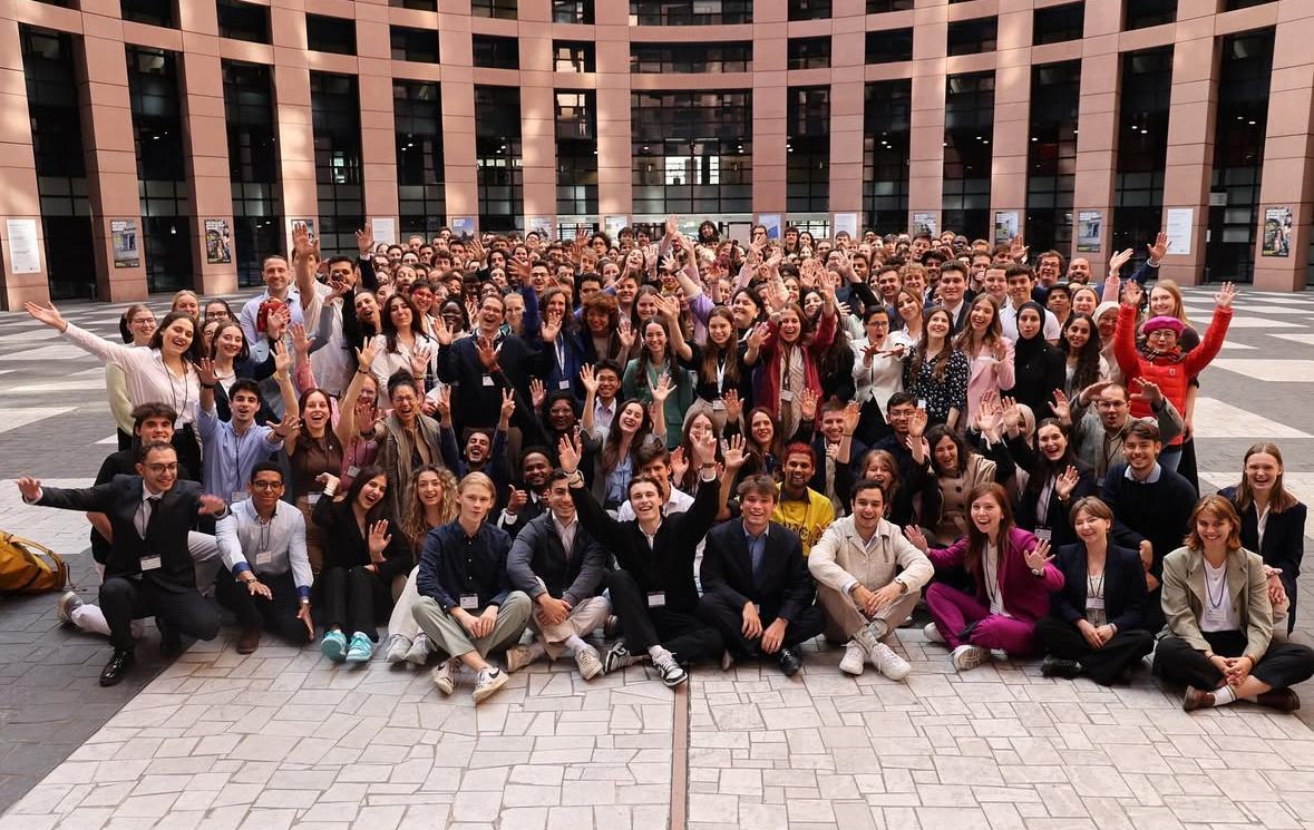 Un gran grupo de personas sonrientes se reúne en un espacio abierto.