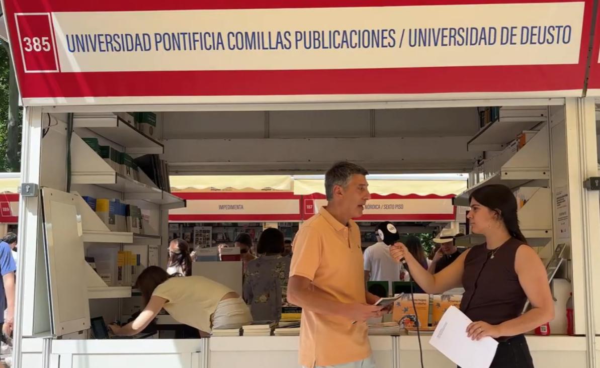 Una mujer entrevista a Carlos Herández Fernández autor de Como hojas en Otoño en la 85ª Feria del Libro de Madrid en un stand de publicaciones universitarias.