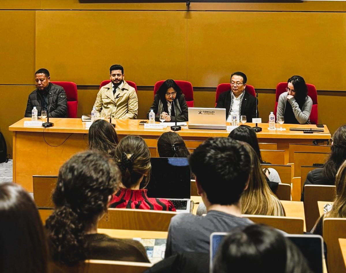 Una mesa de ponentes en un evento académico con varios asistentes en el público.
