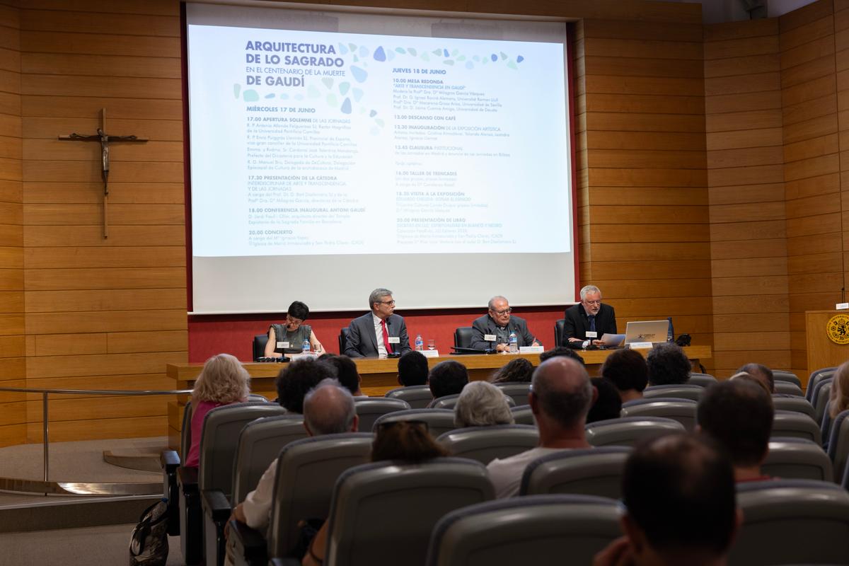 Un panel de expertos discutiendo sobre la arquitectura sagrada de Gaudí en un auditorio.