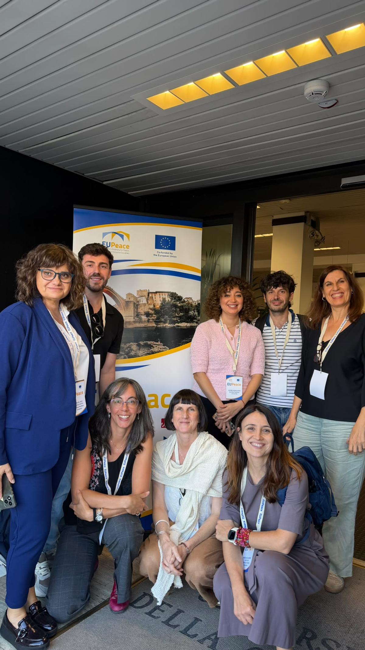 Un grupo de siete personas posan sonrientes frente a un banner en un evento.