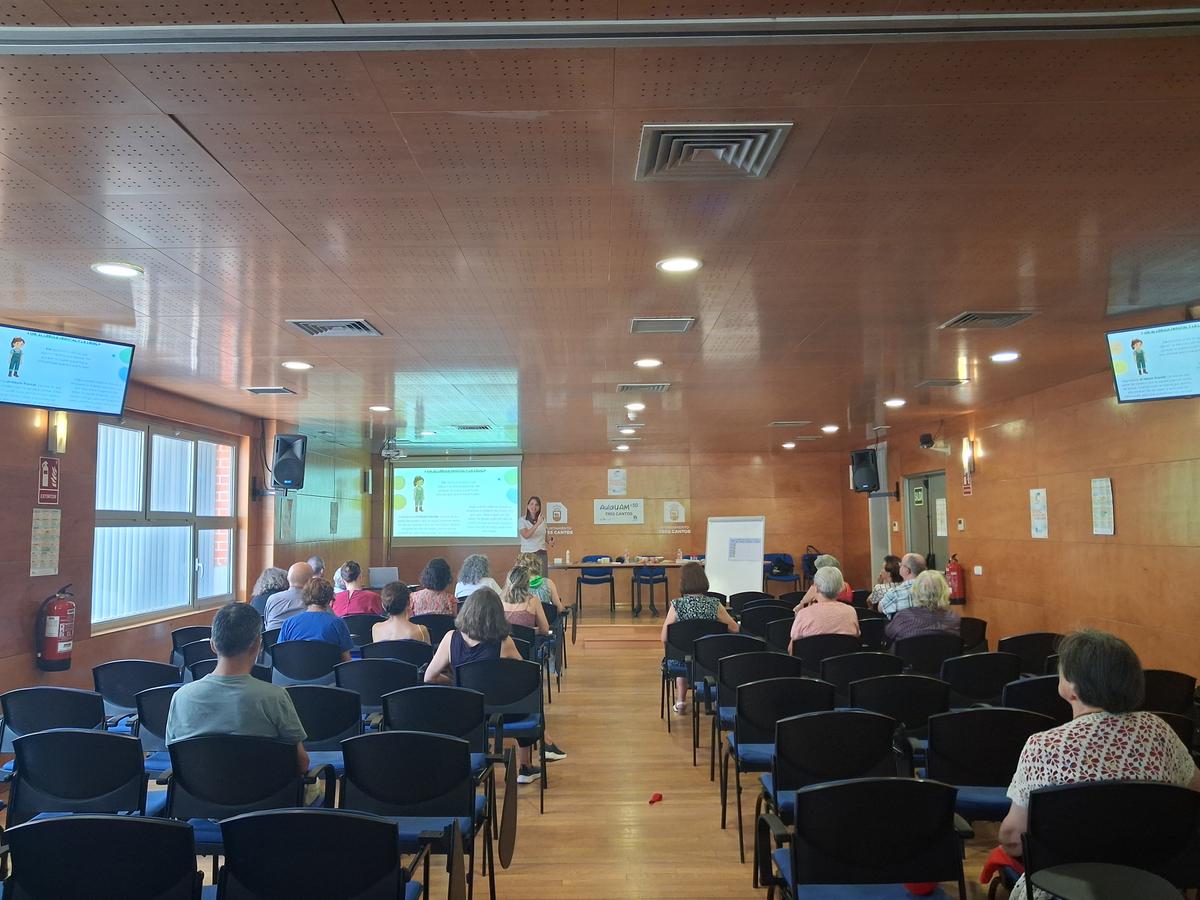 Una presentaci ón en un salón donde un grupo de personas mayores asiste a una charla.