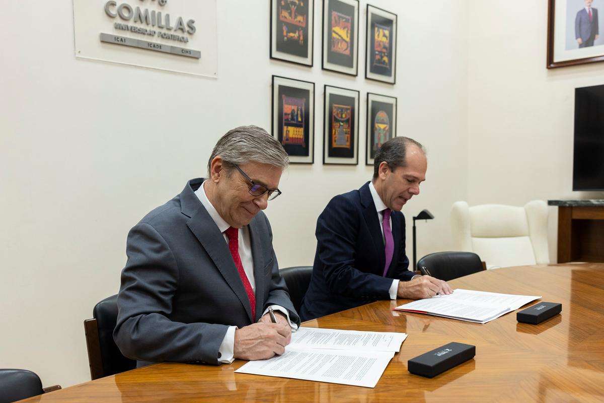 Dos hombres están firmando documentos en una mesa de reunión.