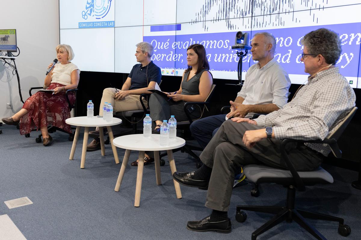 Un panel de discusión con cinco personas sentadas en sillas, en un ambiente académico.