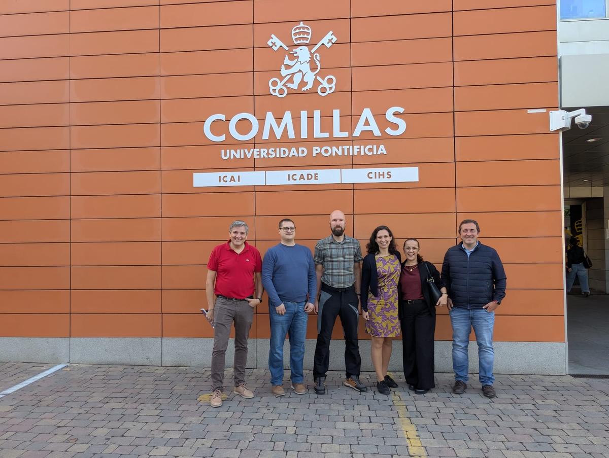 Un grupo de seis personas posa frente a la fachada de la Universidad Pontificia Comillas.