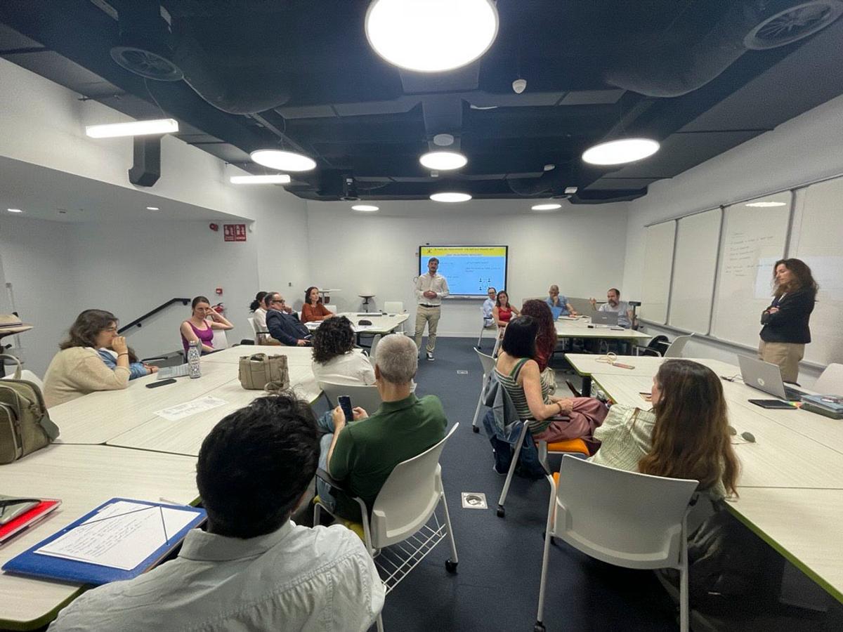 Una reunión en un aula moderna con varias personas sentadas alrededor de una mesa.