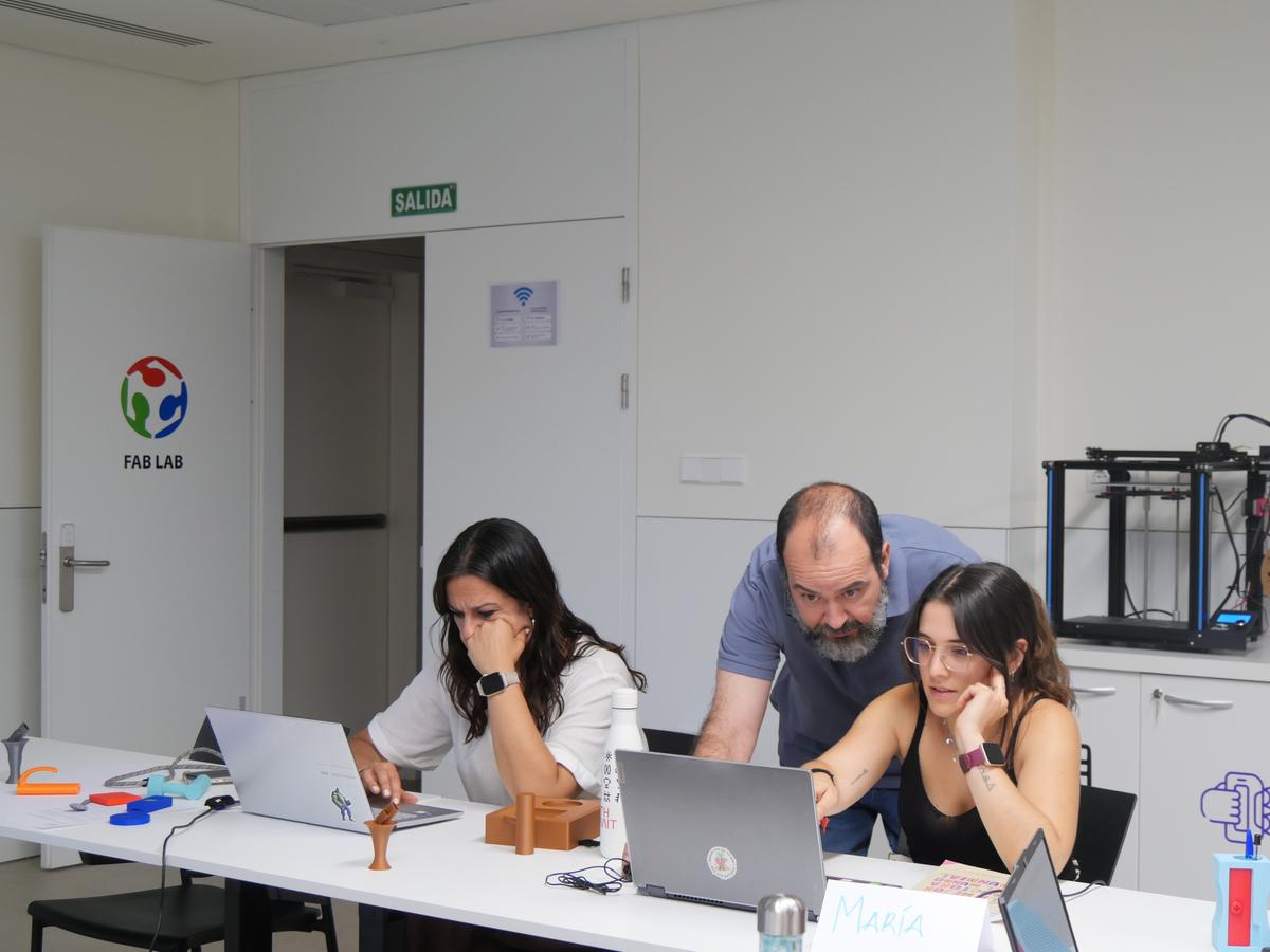 Un grupo de tres personas está trabajando en un laboratorio, utilizando computadoras portátiles y colaborando en un proyecto.