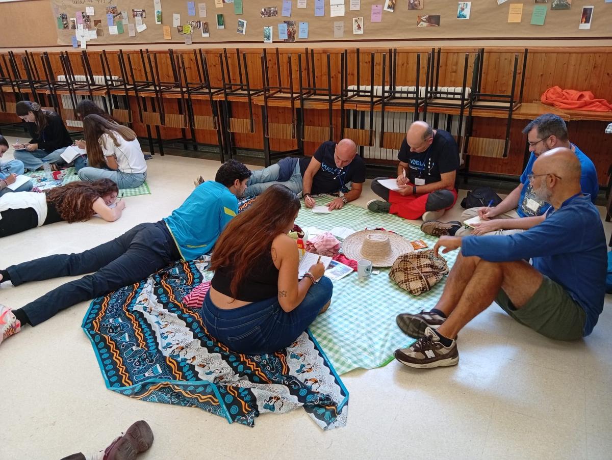 Un grupo de personas sentadas en el suelo, organizando actividades en un ambiente de convivencia.