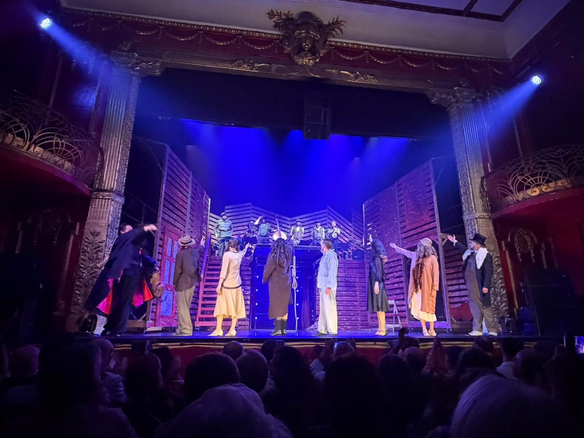 Un grupo de actores se presenta en escena durante una actuación teatral en un teatro.
