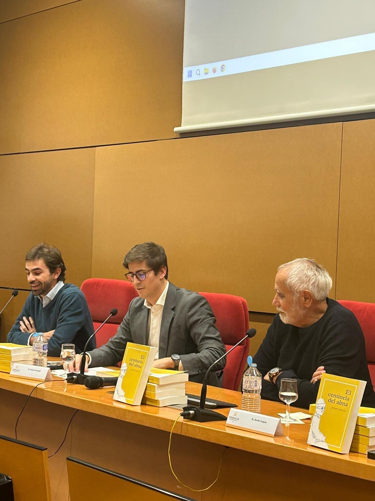 Tres hombres están sentados al frente de una mesa en un evento de presentación de libros.