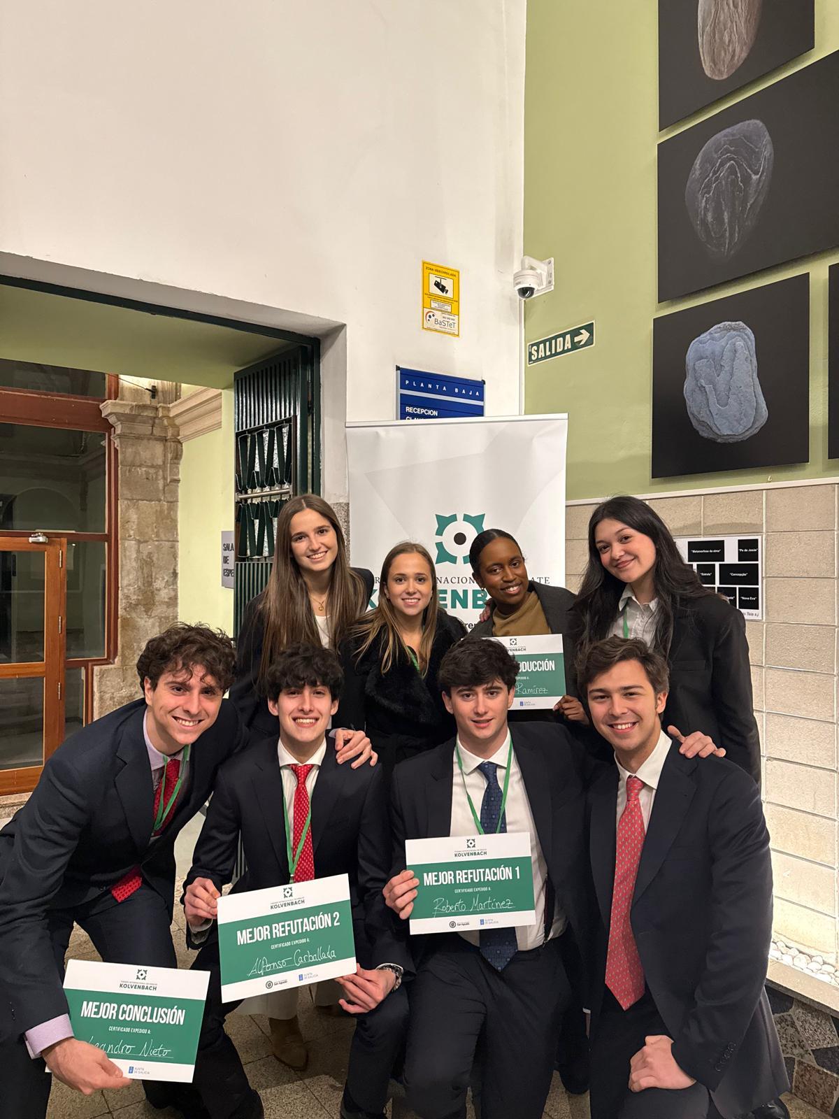 Un grupo de estudiantes sonrientes posando con carteles de reconocimiento en un evento académico.