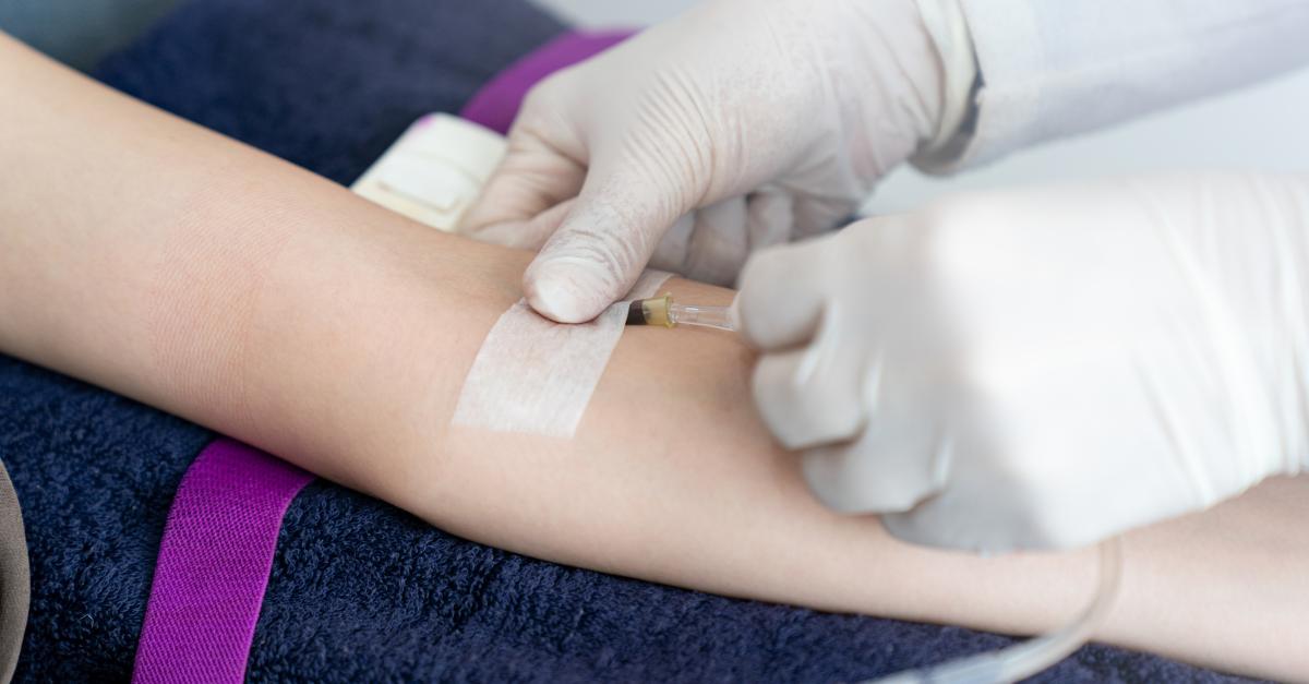Una mano con guantes aplica una inyección en el brazo de una persona.