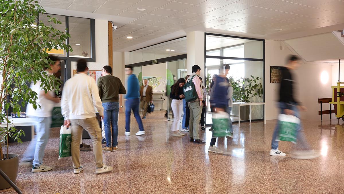 Un grupo de personas se mueve por un espacio interior con plantas y mesas.