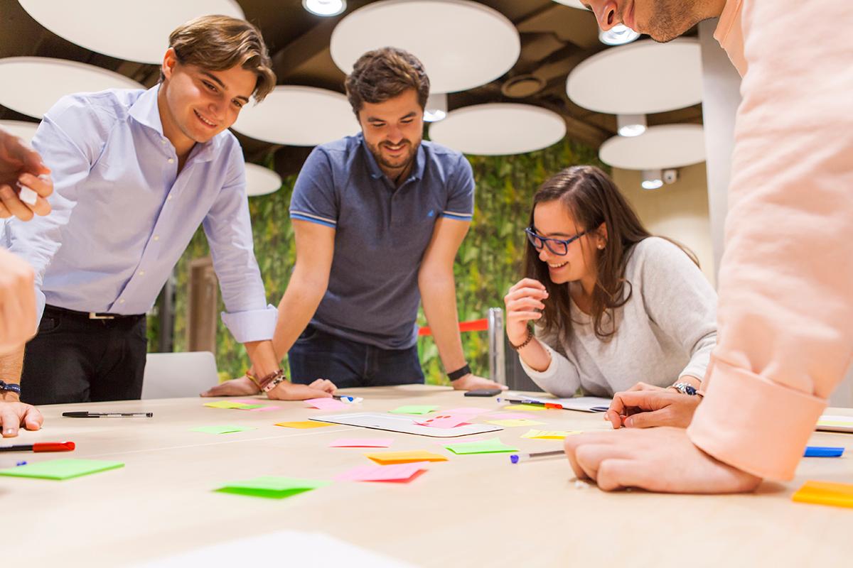 Un grupo de personas colaborando y discutiendo ideas sobre una mesa con notas adhesivas.