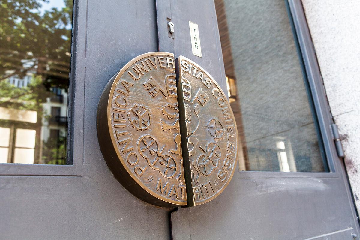 Una puerta con el escudo de la Pontificia Universidad Católica de Chile.